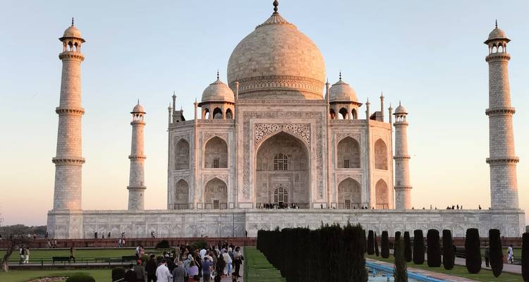 El Taj Mahal brilla con luz cálida mientras los visitantes se alinean en los estanques de reflexión al atardecer