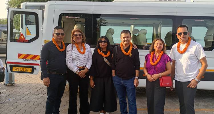 Un grupo de turismo vistiendo guirnaldas de caléndulas posa al lado de su minibús blanco