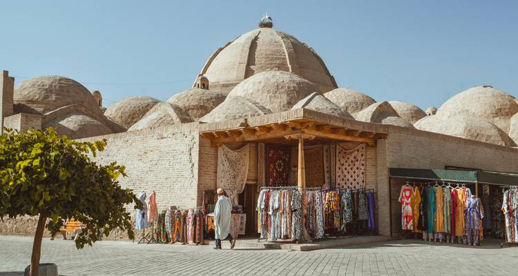 Outside view of a traditional bazaar with domed roofs and colorful textiles displayed.