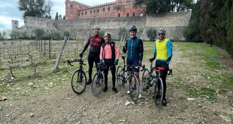Group of cyclists posing in front of a historic castle.