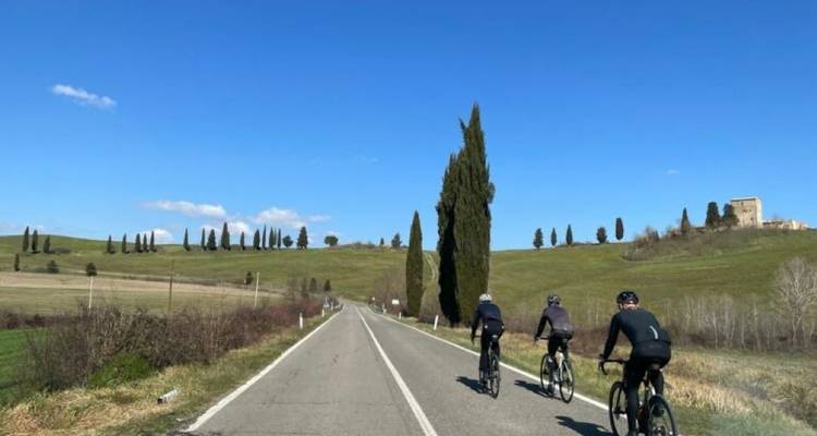 Cyclists on a road through a hilly landscape.