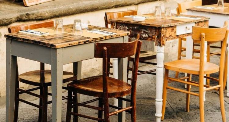 Rustic outdoor cafe setting with wooden tables and chairs.