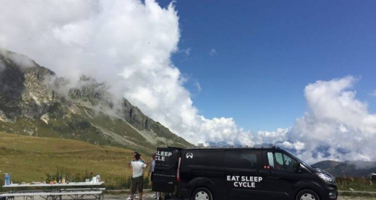 Support van and cyclists resting at a mountain location.