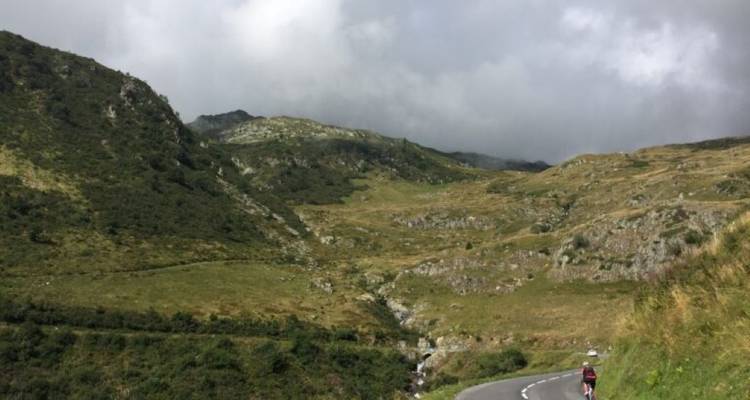 Long road winding through hilly terrain and cyclist riding.