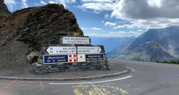 Signpost on a mountainous road with scenic views.