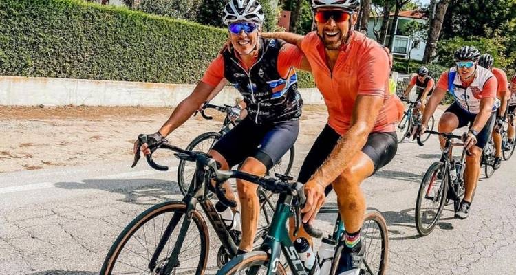 Group of cyclists on a road, smiling at the camera.