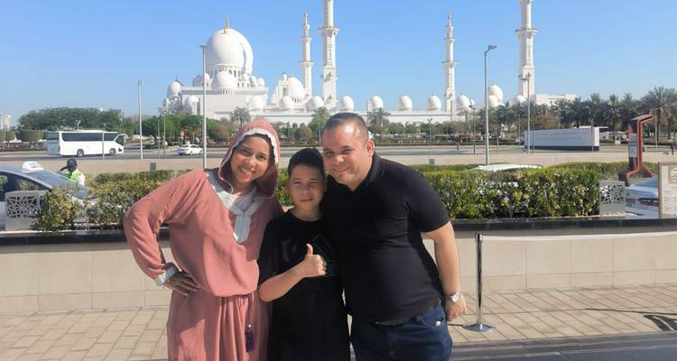 Una familia posando con la Gran Mezquita del Jeque Zayed de fondo.