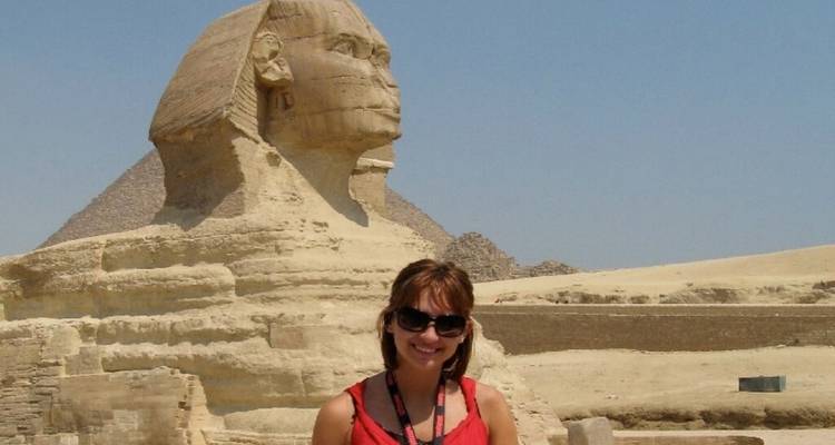 Personne posant devant le Sphinx et la Pyramide sous un ciel bleu dégagé.
