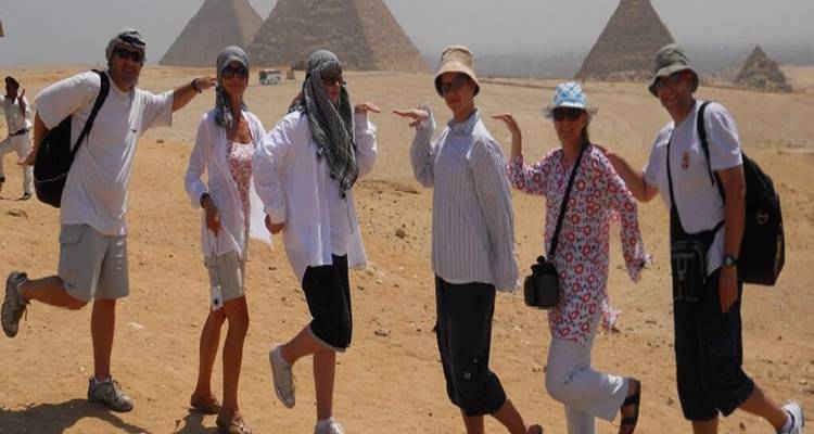 Groupe de personnes posant avec des poses amusantes près des pyramides.