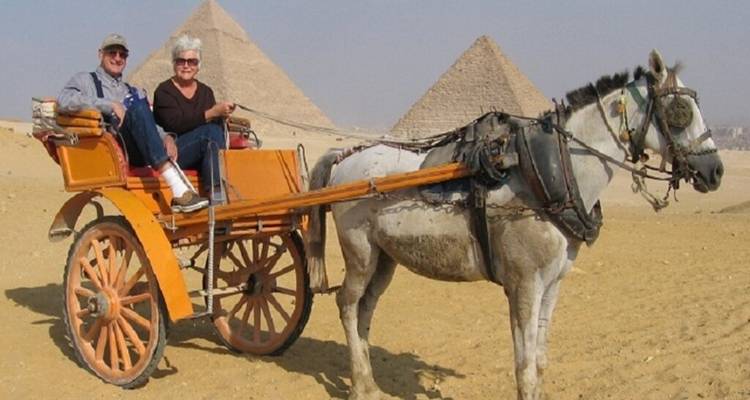 Couple dans une calèche avec des pyramides en arrière-plan.