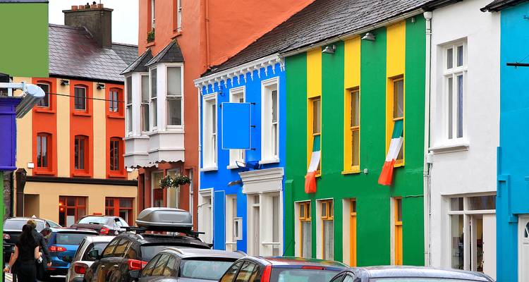 Colorful houses on a bustling street with flags, showing cars parked along the road.