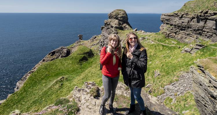 Two people posing on a cliff with ocean views in the background.