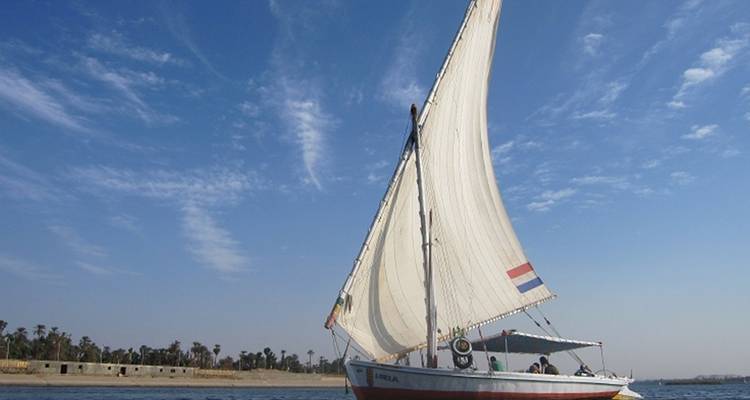 Voilier naviguant sur une rivière avec un ciel dégagé.