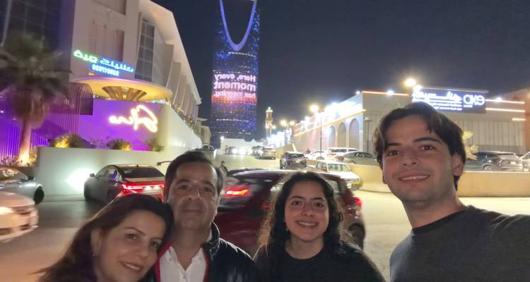 Groepsselfie met een winkelcentrum en wolkenkrabber.