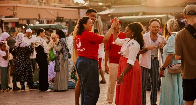 Des amis se tapent dans la main au milieu d'une scène de marché du soir animée sur une place de vieille ville