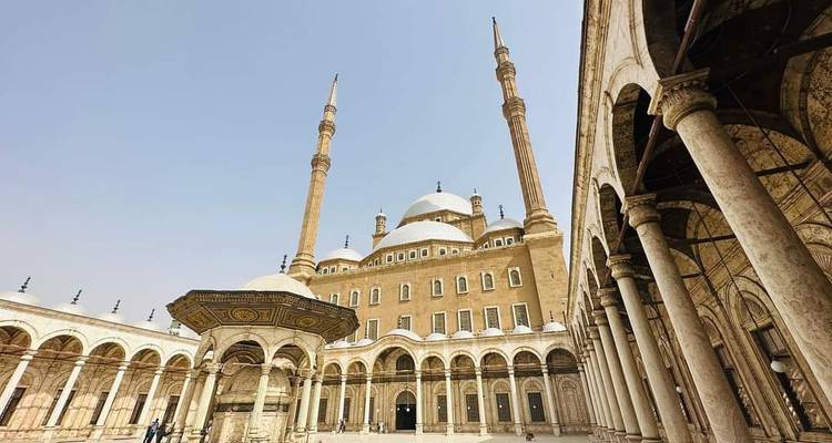 Vue panoramique de la Mosquée Muhammad Ali avec de hauts minarets sous un ciel pâle.