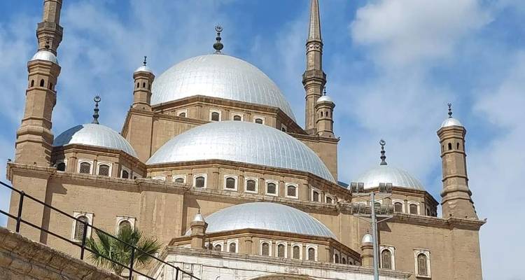 Gros plan sur les dômes et les minarets de la mosquée Muhammad Ali sur fond de ciel bleu.