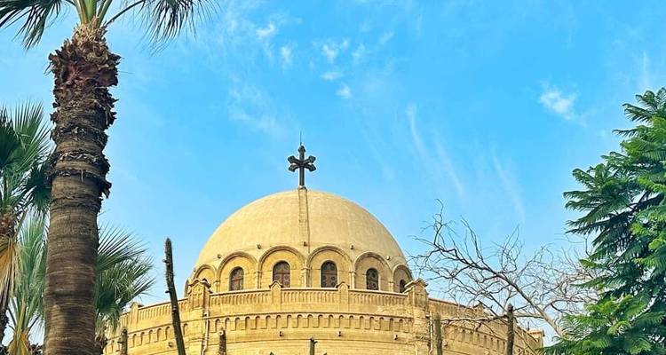 Église à dôme arrondi encadrée par des palmiers sous un ciel bleu éclatant du Caire.