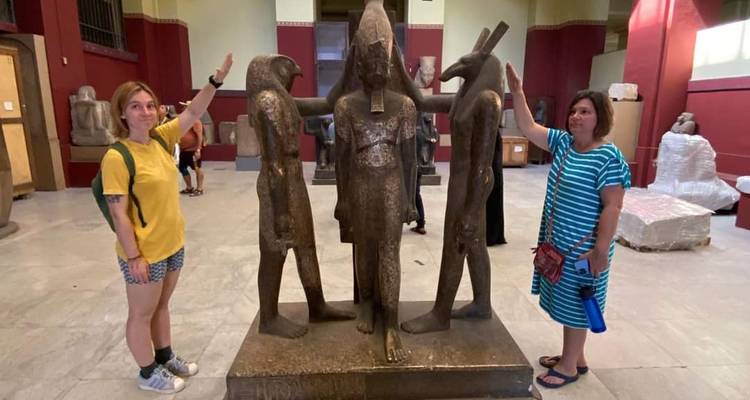 Deux visiteurs imitant une statue antique à l'intérieur du Musée égyptien.