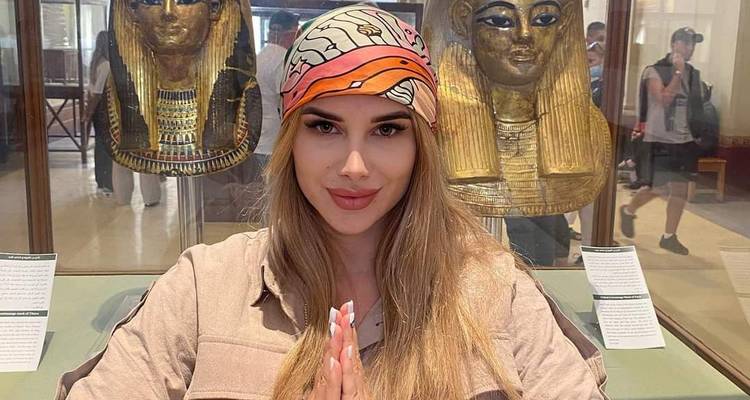 Un visiteur les mains jointes devant deux masques pharaoniques dorés dans un musée.