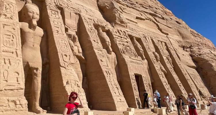 Vue latérale du temple de Néfertari d'Abou Simbel avec des touristes marchant le long des statues.