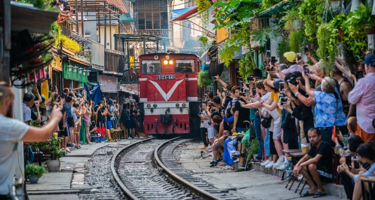 Een trein die door een levendige, drukke straat rijdt.