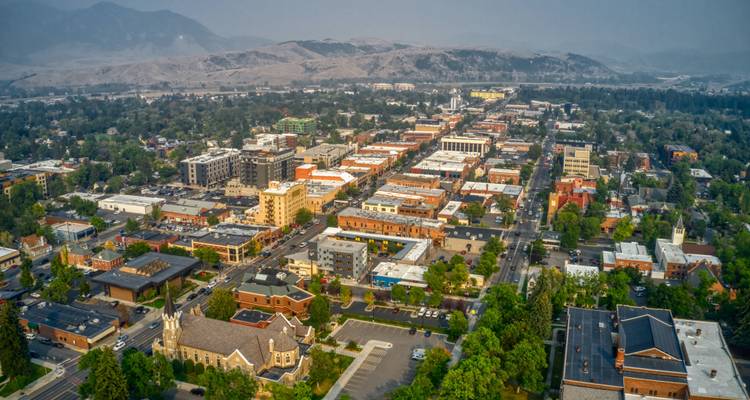 Luchtfoto van een stad omringd door bergen met gebouwen in een rasterpatroon.