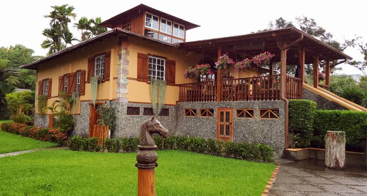 Maison de campagne chaleureuse avec des accents en bois entourée de jardins.
