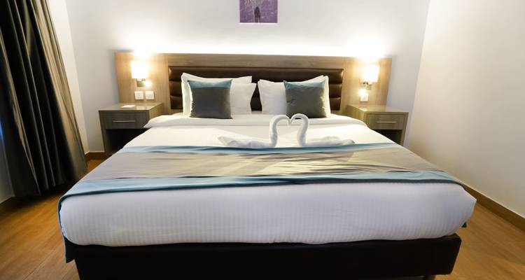 Chambre d'hôtel avec un lit soigneusement arrangé et une sculpture de serviette.