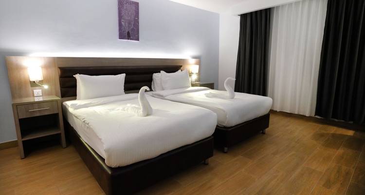 Chambre d'hôtel avec deux lits et literie élégante.