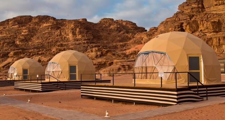 Tentes de désert en forme de dôme installées dans un paysage rocheux.