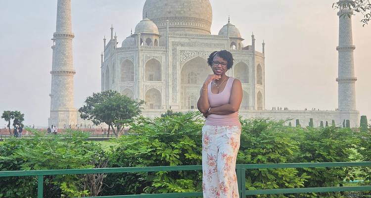 Voyageur posant devant le majestueux Taj Mahal encadré par la verdure lors d'une journée brumeuse.
