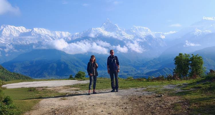 Dos trekistas están de pie en una cresta panorámica con la imponente cordillera del Annapurna detrás de ellos.