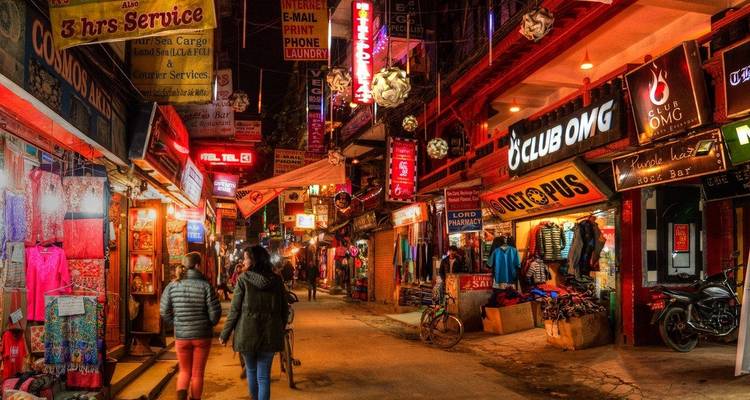 Bustling street market illuminated at night with people strolling.