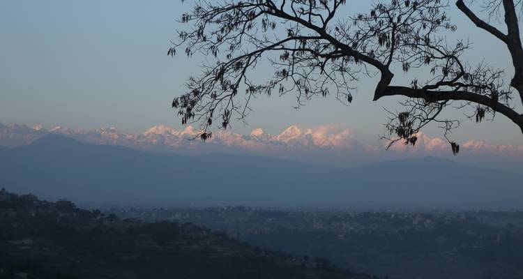 Serene mountain view with snow-capped peaks visible beyond misty valley.