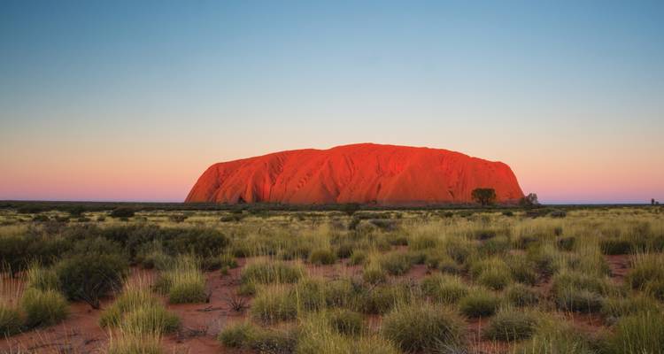 Iconische rode monoliet rotsformatie onder een heldere hemel.