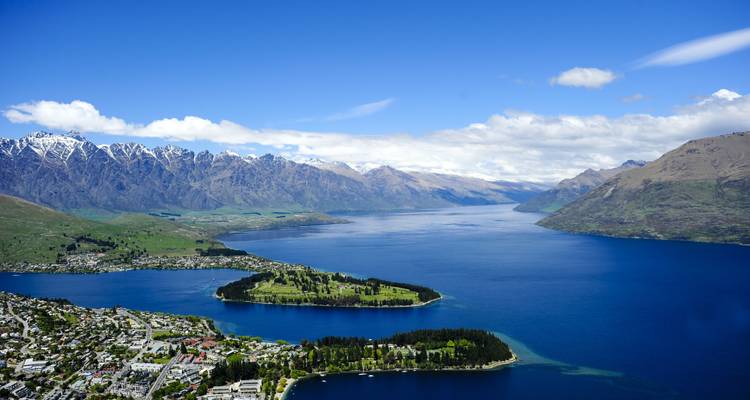 Panoramisch uitzicht op een meer omringd door bergen en een stad.