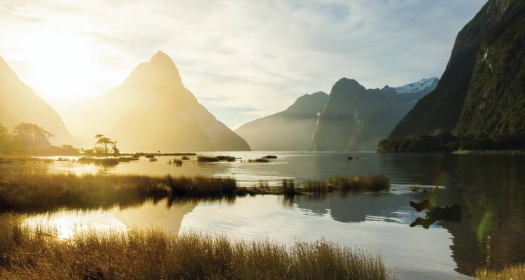Zonsopgang boven een serene meer met bergen op de achtergrond.
