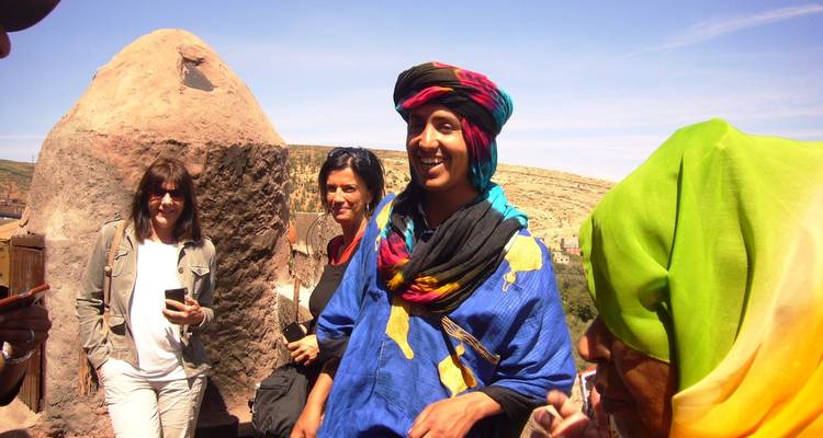 Menschen in bunter Kleidung lächeln im Freien vor Wüstenkulisse.