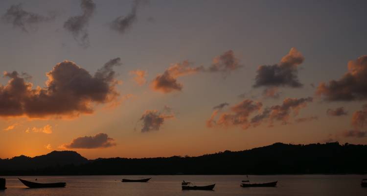 Vue du coucher de soleil sur la mer avec des bateaux en silhouette.