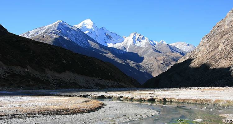 Berglandschaft mit einem Fluss im Vordergrund.