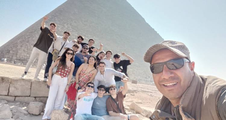Group of people posing in front of a pyramid.