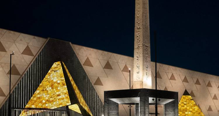 Modern museum facade with pyramid-like structures at night.