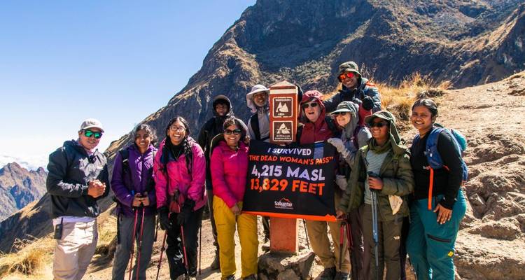 Grupo de excursionistas posando con un letrero en el Paso de la Mujer Muerta.