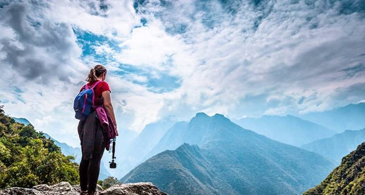 Mujer con una mochila contemplando las montañas.