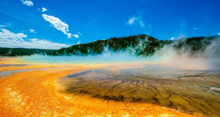 Brightly colored geothermal spring with steam rising.
