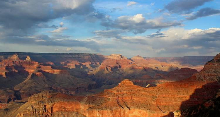 A vast canyon landscape under a cloudy sky.
