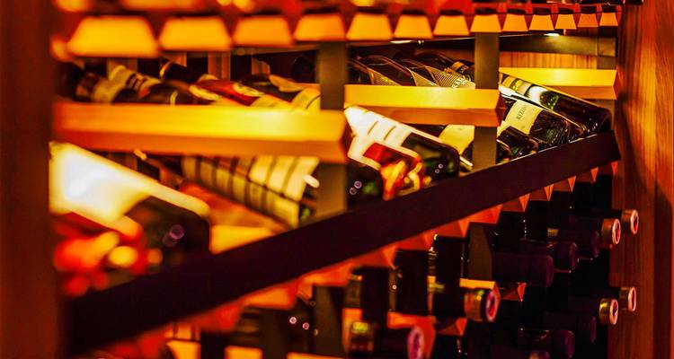 Close-up van wijnflessen op een rek met warme verlichting.