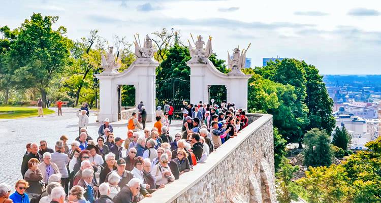 Menigte toeristen bij een sierlijke poort met uitzicht op de stad.