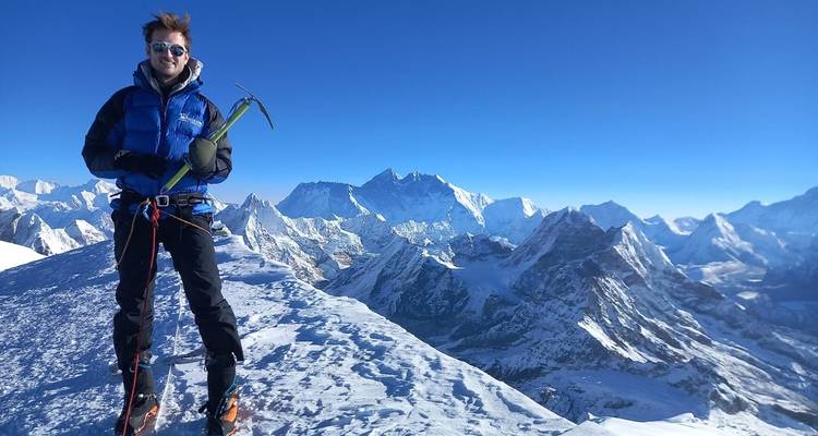 Een klimmer op een besneeuwde top met adembenemende bergzichten.